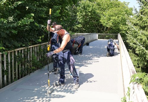 Die Fachfirma trägt eine Schutzschicht auf dem neuen Belag auf. (Foto: Stadt Siegen)