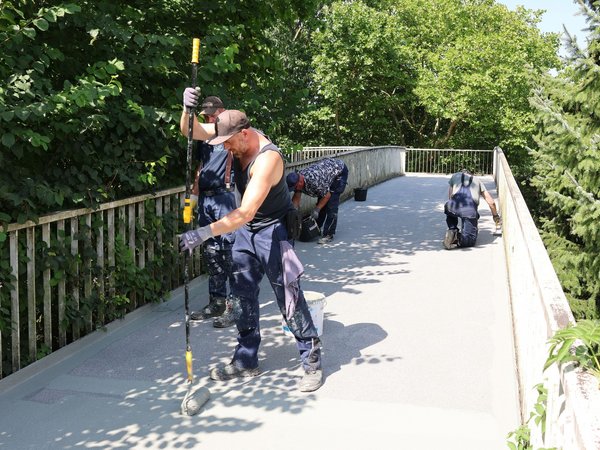 Die Fachfirma trägt eine Schutzschicht auf dem neuen Belag auf. (Foto: Stadt Siegen)