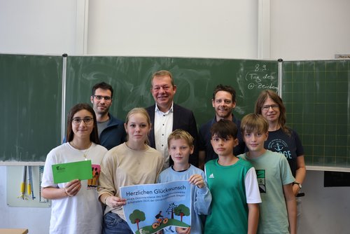 (v.l.) Hendrik Kölsch (DAV), Bürgermeister Steffen Mues, Jan König (Mobilitätsmanager) und Judith Zeller (Klassenlehrerin 7e) überreichen den Hauptpreis an die Schülerinnen und Schüler.