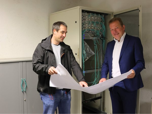 Stefan Erben (TGW) berichtet Bürgermeister Steffen Mues im Serverraum der Albert-Schweitzer-Schule über die umgesetzten Maßnahmen. (Foto: Stadt Siegen)