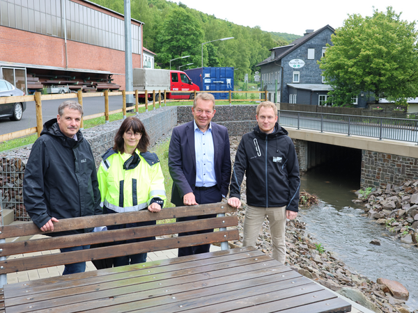 Stephan Roth (ESi), Renate Brühl (ESi-Projektleiterin), Bürgermeister Steffen Mues und Björn Winter (Planungsbüro BauPlan) (v.l.) an der neuen Sitzgruppe neben dem renaturierten Eisernbach. (Foto: Stadt Siegen)