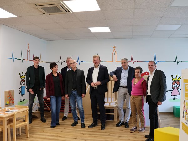 Die städtischen Akteure aus der Kinder-, Jugend- und Familienförderung, NRW-Staatssekretär Lorenz Bahr (3.v.r.) und Bürgermeister Steffen Mues (4.v.r.) vor der Preisübergabe im Familienbüro in Weidenau. (Foto: Stadt Siegen)