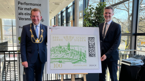 Bürgermeister Steffen Mues (l.) und Dr. Fabian Leber, Sprecher des Bundesfinanzministers, (r.) präsentieren die offizielle Sonderbriefmarke zu Siegen800 (Foto: Stadt Siegen)