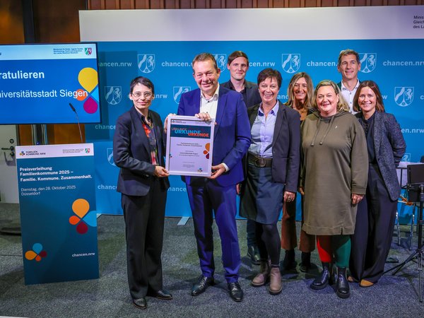 Familienministerin Josefine Paul (l.) überreichte Bürgermeister Steffen Mues und dem Team aus Siegen die Siegerurkunde als „Familienfreundliche Kommune 2025“. (Foto: R. Oberhäuser | MKJFGFI)