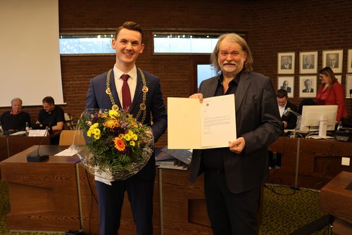 Bürgermeister Tristan Vitt mit Amtskette und Blumenstrauß, kurz nach seiner Vereidigung durch den Altersvorsitzenden Michael Groß. (Foto: Stadt Siegen)