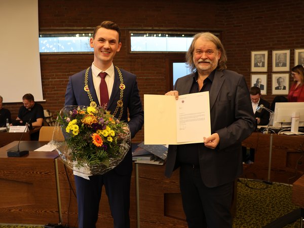 Bürgermeister Tristan Vitt mit Amtskette und Blumenstrauß, kurz nach seiner Vereidigung durch den Altersvorsitzenden Michael Groß. (Foto: Stadt Siegen)