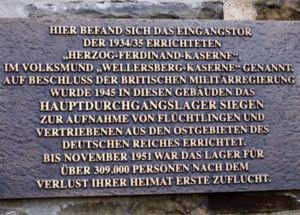 Gedenktafel zur Erinnerung an die Wellersbergkaserne (ab 1938 Herzog-Ferdinand-Kaserne) und das Hauptdurchgangslager Wellersberg (1945/1946 bis 1951) an den restaurierten Fragmenten des früheren Haupteingangsportals, Foto: Stadt Siegen