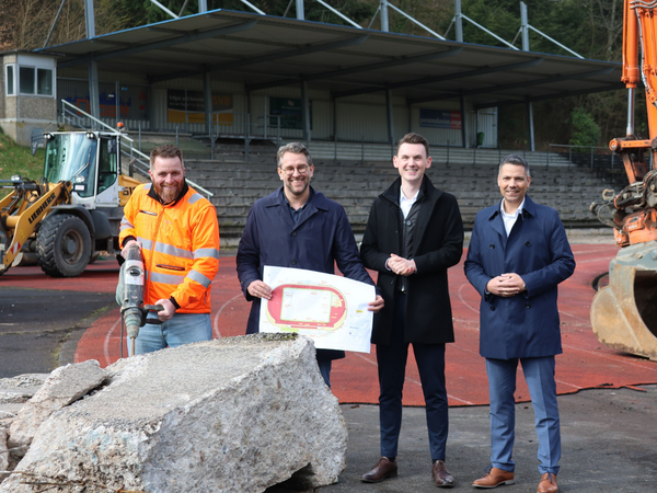 Baustart im Hofbachstadion: Sebastian Deppe (Strabag Sportstättenbau), Stadtbaurat Henrik Schumann, Bürgermeister Tristan Vitt und Stadtrat Adrian Viteritti (v.l.) im Stadion, wo die Bagger bereits brummen. (Foto: Stadt Siegen)