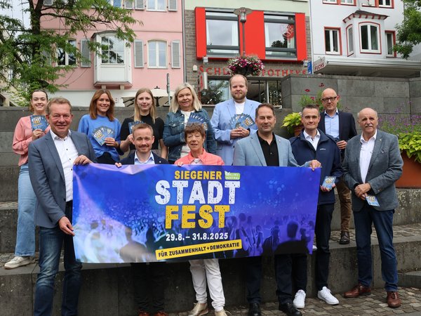 Vorfreude auf das diesjährige Stadtfest: Bürgermeister Steffen Mues (links) und die Verantwortlichen. Partner und Sponsoren. Untere Reihe (v. l.): Bürgermeister Steffen Mues, Sebastian Quast/Bauunternehmen Otto Quast, Astrid Schneider/KulturSiegen, Stadtrat Arne Fries, Stephan Boch und Gerhard Bettermann/beide VWS. Obere Reihe: Nives Carstensen/KulturSiegen, Daniela Hilgendorff/Familienbüro Stadt Siegen, Carla Wiesener/ SVB, Tanja Herdlitschke/Sparkasse Siegen, Patrick Plate/Westenergie, Michael Göttert/Siegener Zeitung (Medienpartner). (Foto: Stadt Siegen)