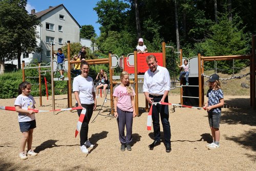 Die Schülerinnen und Schüler der Albert-Schweitzer-Schule haben den Spielplatz gemeinsam mit Manuela Haas, Leiterin der städtischen Grünflächenabteilung und Bürgermeister Steffen Mues eröffnet und direkt ausprobiert. (Foto: Stadt Siegen)