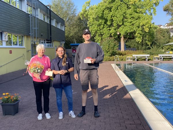 Margret Henß (l.) und Martin Müller (r.) erhalten die beiden Hauptpreise von Katharina Sierpinski (Betriebsleitung Freibad Kaan-Marienborn). (Foto: Stadt Siegen)