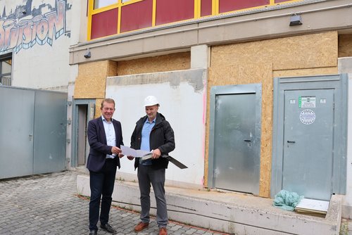 Bürgermeister Steffen Mues und der Projektverantwortliche Dennis Päulgen machen sich ein Bild der Sanierung der Außentoiletten der Bertha-von-Suttner-Gesamtschule. (Foto: Stadt Siegen)