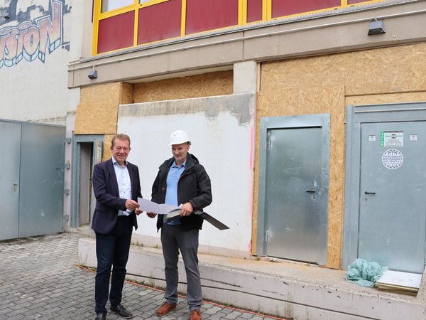 Bürgermeister Steffen Mues und der Projektverantwortliche Dennis Päulgen machen sich ein Bild der Sanierung der Außentoiletten der Bertha-von-Suttner-Gesamtschule. (Foto: Stadt Siegen)