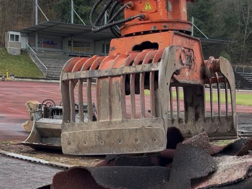 Ein Bagger beseitigt die Reste der alten roten Tartan-Bahn im Hofbachstadion. (Foto: Stadt Siegen)